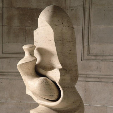 A modern abstract sculpture made of stone, placed on a circular base. The sculpture has smooth, curved surfaces and appears to be an intricate, intertwined form. There is a small plaque on the base of the sculpture with the text 'MOTHER AND CHILD HENRY MOORE.' The sculpture is situated in a dimly lit room with stone walls and a tiled floor, with light casting shadows on the sculpture and the floor. The interplay of light and shadow highlights the smooth texture and curves of the sculpture, making it visually interesting.