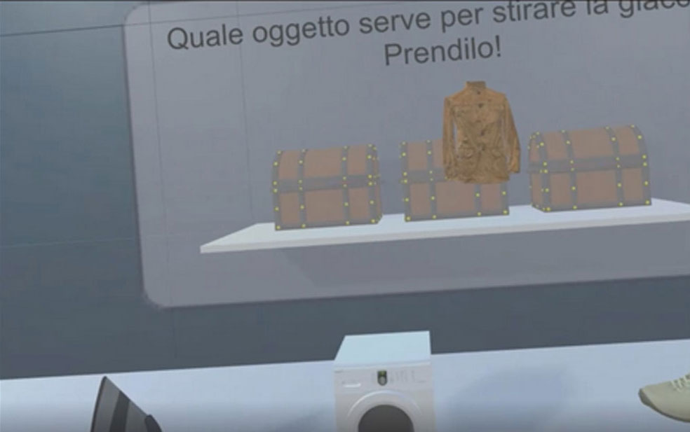 A scene showing a shelf with three objects: two chests and a jacket. Above the shelf, there is text in Italian that reads: 'Quale oggetto serve per stirare la giacca? Prendilo!' which translates to 'Which object is needed to iron the jacket? Take it!' Below the shelf, there is a washing machine. The image appears to be part of an interactive or educational activity where the viewer is asked to identify the object needed to iron the jacket.