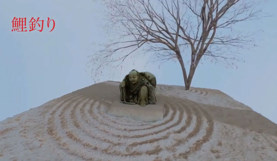 A statue of a person kneeling on a platform in a Zen garden. The garden features concentric circles raked into the sand, and there is a leafless tree in the background. In the top left corner, there is Japanese text written in red, which reads '鯉釣り (Koi Tsuri),' translating to 'Carp Fishing